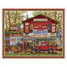 The cross stitch project featuring a country store with lots of signage, a bike and a red truck parked out front, finished with a wooden frame.