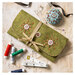 The completed Sewing Roll tied up and sitting on a table surrounded by sewing notions. 