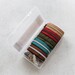 An open plastic case holding assorted colorful zippers and pulls.