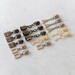 Assorted metal zipper pulls in gold, nickel, and gunmetal, displayed neatly on a white countertop.