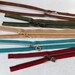 Five zipper pieces in various colors arranged horizontally, showing their coordinating novelty zipper pulls.
