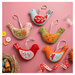 The completed folk bird ornaments on a table surrounded by sewing notions. 