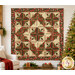 The completed Cactus in the Cabin quilt, colored in red, cream, sage green, and soft black metallic fabrics from the Merry Manor Metallic 2025 collection from Moda Fabrics. The quilt is hung on a cream wall and staged with coordinating holiday decor.