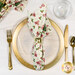 A top down shot of the napkin with the cream fabric facing out, staged on a coordinating gold table setting on a white marbled