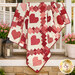 The completed Heartsy Quilt, artfully draped over a white porch railing with coordinating décor and flowers.