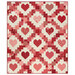 The completed Heartsy Quilt, colored in pink, red, and cream fabrics from the Petals and Polka Dots collection by Moda Fabrics, isolated on a white background. 