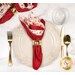 A top down shot of the napkin with the red side out, showcasing the geometric print; the napkin is staged with a cream plate and matching table setting.