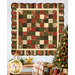 The completed Holiday Charm Quilt, colored in cream, green, and red fabrics from the Merry Manor Metallic 2025 collection, hung on a white shiplap wall and staged with coordinating décor and a lit Christmas tree.