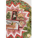 A stylized close up on the topper, showing details on the fabric colors and prints; a sprig of holly peeks into frame from the left side.