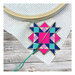 The quilt star needle miner displayed on a hand embroidery project.