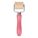 A pink-handled roller with a metal frame and a cylindrical wooden roller at the top on a white background