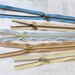 Five zipper pieces in various colors arranged horizontally, showing their coordinating novelty zipper pulls.