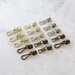 Assorted metal zipper pulls in nickel, gold, and antique, displayed neatly on a white countertop.