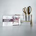 The bamboo scissor stand packaging on a table next the built scissor holder with scissors in the holder.  