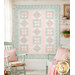 The completed Pink Diamonds quilt, colored in elegant pink, cream, and blue fabrics from the Abide collection by Moda Fabrics, hung on a white shiplap wall and staged with coordinating furniture and décor.