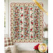 The completed Christmas Lane Quilt, colored in cream, green, red, pink, and blue fabrics from the Christmas Greetings collection by Riley Blake Designs, staged on a white porch wall with coordinating décor.