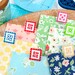 The quilty clips marking fabrics on a sewing table surrounded by notions and fabrics. 