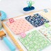 The quilty clips marking fabrics on a sewing table surrounded by notions and fabrics. 
