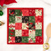 The completed Fusible Grid Hot Pad colored in red, green, black, and cream fabrics from the Holiday Cheer collection by Moda Fabrics. The project is staged on a whit marbled table where a wooden spoon and Christmas décor peek into frame.