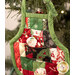 An angled close up on the front of one of the Christmas Apron Ornaments, showing fabric and top quilting details, as well as dimensional pocket details where a chocolate Santa peeks out.