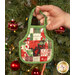 A model holds one of the Christmas Apron Ornaments in front of a tree, demonstrating scale of the project.