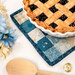 A close up on the hot pad, staged with a fresh baked pie, showing details on the fabrics and binding.