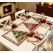 The completed Tree Farm Table Runner colored in cream, red, green, and black fabrics from the Candlelight Christmas collection by Moda Fabrics, staged on a white table in a cozy room with four coordinating table settings..