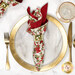 A top down shot of the napkin with the cream fabric facing out, staged on a coordinating gold table setting on a white marbled table.