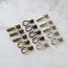 Assorted metal zipper pulls in nickel, antique, and gunmetal, displayed neatly on a white countertop.