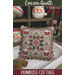 Decorative quilted pillow with red and green geometric pattern, displayed on a white chair.