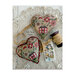 Finished Folk Floral Heart Ornament cross stitch pattern, on a lace doily surrounded by tan ribbons and a photograph.