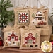 The four completed Farmhouse Christmas Cross Stitch Ornaments, stitched on beige aida cloth in Christmas colors, staged on a brown box with coordinating trees.