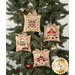 The four completed Farmhouse Christmas Cross Stitch Ornaments, staged on a decorated green Christmas tree. 