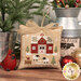 A close up on a completed ornament, featuring a red farmhouse with green doors, surrounded by two sheep and a cardinal.