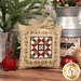 A close up on a completed ornament, featuring a red, green, and white quilt block with cute green border details.