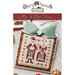Front cover with a finished Mr. & Mrs. Claus cross stitch pattern on an envelope topped with a bow surrounded by Christmas bells.