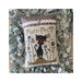 Finished Purr-Fect! cross stitch pattern of a black cat walking through a flower field topped with a pink lace fabric and heart charm stitched onto a pillow.