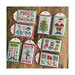 Finished Christmas Tiny Tags cross stitch project with all sorts of Christmas motifs and phrases laid out on a wood plank backdrop.