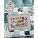 Finished Bessie in the Bluebells pattern of a shepherd herding cows in front of cottages surrounded by an ornamental white accent laying on a blue and white quilt.