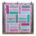 Finished The Big Easy pattern with purple and teal tone fabrics hung on a wooden fence.