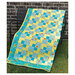 Finished Cornerstones quilt in a turquoise and yellow fabrics hung on a metal bench.