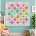 The completed Legendary quilt, colored in bright classic Tula colors, set against an aqua wall in a complementary styled room