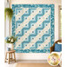 The completed Log Cabin Throw Size Quilt, colored in blue and cream fabrics from the Sewing Bird collection by Andover Fabrics, staged on a cream wall in a brightly lit room with coordinating décor. 