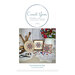 Front cover of three different finishing variations for the Summertime Star cross stitch pattern sitting next to white doilies, scissors, buttons, a vase, and in front of a white wooden wall.