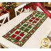 The completed A Gift for You Table Runner, colored in red, green, and white, and gold metallic fabrics from the Poinsettias at Christmas collection by Jennifer Bosworth for Riley Blake Designs, staged on a white table with four coordinating settings and napkins.