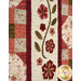 A close up on the quilt, showing details on the appliqué flowers and patchwork rows of the quilt.