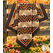 The completed Log Cabin Throw Quilt, colored in black, brown, tan, orange, and cream fabrics from the Midnight Cheddar collection from Marcus Fabrics, artfully draped over a rustic wooden farm fence outdoor on a sunny autumn day.