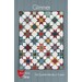 The front of the Glimmer pattern with the completed quilt hung up on a blue wooden wall.