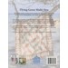 The back cover of the pattern book, showing on of the quilts draped across a tree branch on the beach.