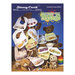 Front cover of the Nothing But Bibs cross stitch pattern showing the 12 finished designs hanging on an assortment of stuffed animals.